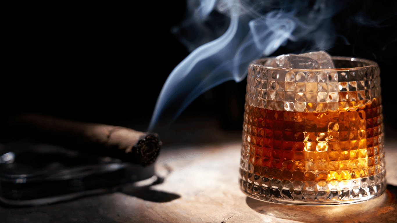 Lit Cigar with glass of Bourbon